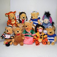 Photo showing all nine plush toys including Pooh dressed as Tigger, pilot Pooh, sailor Poohs, Cupid Eeyore, prisoner Pooh, reindeer Pooh, family Pooh, fireman Tigger.