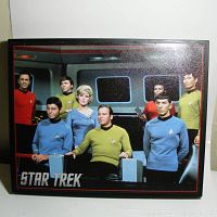 Front view of the laminated color photo print of the Star Trek Original Series cast on the bridge set, mounted on black frame with 'Star Trek' text in lower left corner.