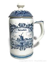 Front view of Delft-style stein showing windmill scene with Heineken banner, lid, and handle.
