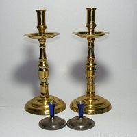 Pair of solid brass 12-inch candlestick holders alongside pair of small silver plated 3-inch candle holders with blue candle cups.