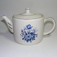Full side view of the white ironstone teapot showing the blue floral design and gold accents on spout and lid.