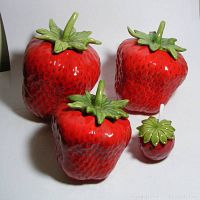 Photo showing the 3 large strawberry-shaped ceramic canisters along with small strawberry jam jar on white background.