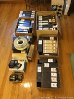 Multiple cardboard boxes on hardwood floor containing Sawyer slide trays, carousel trays and two handheld viewers