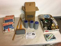 Full view showing three packages of Roll A Tex paint roller covers, paint roller with handle, extension handles, paint roller sleeves, original Paint Runner box, and a box of assorted painting accessories