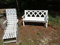 Two white aluminum benches and one white folding chaise lounge chair set outdoors on grass/dirt surface. Benches show lattice back design and peeling white paint.