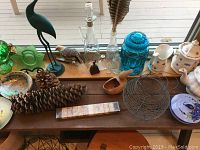 Assorted decorative items on a window ledge including glass jars, ceramic pitchers, wooden figurines, and metal basket