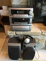 Photo of a JVC stacked stereo system with record player on top, dual cassette decks in the middle, CD player on the bottom. Two speakers sit in front, with one having headphones resting on it.