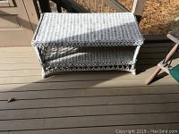 Side view of the wicker table showing woven wicker sides and lower shelf.