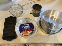 Photo showing cast-iron cornbread pan, disposable aluminum pie pans, and two springform cake pans