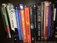 Books focused on finance, stocks, investing, and economic themes, arranged vertically on a shelf.