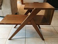 Wooden side table with angled X-style legs and open shelves.