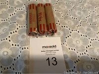 Three rolls of wheat pennies with paper wrappers on crocheted white tablecloth, with one roll marked '194x'.