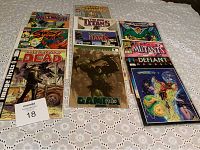 Overview of multiple comic books arranged on a table, each in a plastic sleeve.