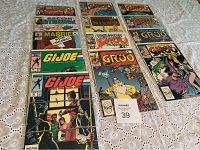 Full view of comic books including G.I. Joe and Groo series in plastic sleeves on lace tablecloth.