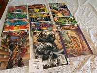 Photo showing assorted comic books including Millennium, Drifter, Moon Knight, and Warlord in plastic sleeves on a bedspread