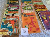 Collection of older comic books laid out on a lace cloth, includes Manhunter, Archie, Smurfs, Richie Rich, Pink Panther, Underdog, and Sad Sack titles.