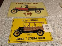 Photo of two Ford tin signs on lace tablecloth, featuring Ford One-Ton truck and 1925 Model T Station Wagon illustrations with pricing.