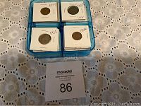 Blue container holding individually housed U.S. coins, view from above showing four sections with coins labeled by year.