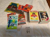 Photo displaying various closed and opened packs of sports trading cards on a white surface. Includes visible brands and player cards like Alan Trammell and Randy Johnson.