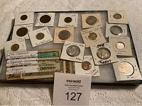 Overview of foreign coins and currency from multiple countries, many coins in protective holders.