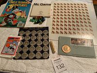 Full view of all items included in the lot arranged neatly on a white textured cloth, showing comic, game, marbles, stamps, coin collection, gold flakes, hockey cards, and first day cover.