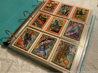 Binder open showing trading cards inside plastic sleeves, featuring GI Joe cards with military characters and vehicles.