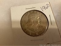 Front close-up of 1960 Franklin half dollar coin in cardboard holder showing obverse with Benjamin Franklin portrait, date 1960, and inscriptions.
