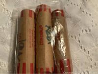 Three wrapped rolls of pennies labeled Containerm® with markings indicating 1930s pennies