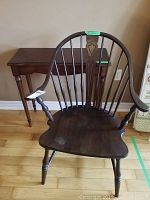 Front view of vintage Windsor style chair showing curved back with spindles and carved central splat, turned legs, and arm supports.