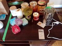 Full view of assortment including wax bars, jar candles, glass votive, pillar candles, and plug-in warmer on table