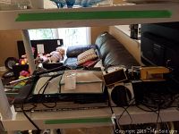 Shelf with Sharp DVD player, remote, irons, clock, solar lights and cables.