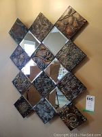 Front view of the diamond shaped metal and mirror wall art installed on the wall.