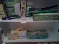 Shelving with Swiffer Sweeper 64 refill box, Swiffer Sweeper tool with handle, Swiffer Dusters refills box and other cleaning supplies.