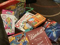 Various board games and puzzles arranged including Barbie T-Shirt Designer, Minion Operation, and a Cars puzzle