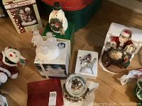 Overview of lot showing snowmen statues, Santa Claus statue, two snow globes and original boxes in background.