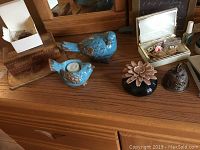 Wood box, brass bell, small trinket box, quilled box with pins, and blue bird tea light holder on wooden dresser surface.