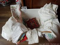 White and cream vintage handkerchiefs with lace and crochet edges, plus a red plaid handkerchief on a wooden surface.