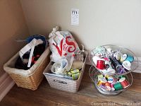 Overview of baskets and containers holding sewing supplies including threads and pins