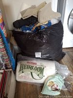 Full view of the large black bag filled with stuffing and poly pellets, Hobbs cotton batting roll and small package