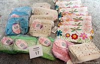 Large assortment of cosmetic bags and pencil cases grouped by color and pattern on carpeted floor.