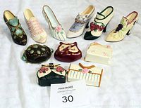 Photo showing six vintage-style shoe figurines each paired with miniature matching purse figurines, displayed on white fabric background.