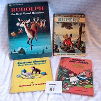 Photo showing four vintage children's books: Rudolph the Red-Nosed Reindeer, Rupert, Curious George Goes to the Hospital, and Raggedy Ann and Andy's Animal Friends on a light surface.