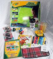 Photo showing Crayola Glow Station boxed kit along with assorted art supplies arranged neatly including markers, crayons, coloring books, chalk sticks, stamps, and pencil case.