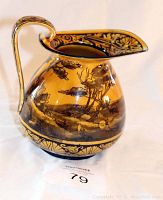 Full side view of the amber ceramic pitcher showing the tree landscape and floral designs