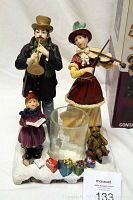 Full view of the Carollers Hurricane Candle Holder showing the three porcelain figurines, glass hurricane candle holder, gifts, and teddy bear on snowy base.