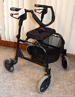 Black Nexus mobility walker with removable mesh basket and padded seat shown from a side/front angle on carpet.