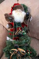 Close-up showing Santa Claus figure holding reins, detailed face with glasses and white beard, wearing red and fur-lined clothing.