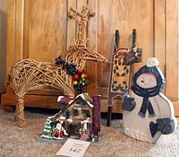 Photo showing all four items: vine reindeer, wooden snowman, wooden sleigh candle holder, and log cabin Christmas scene