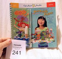 Front cover of the Chicken Socks Mermaid's Palace activity book showing the title, brand, and a child holding the completed palace craft.