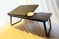 Front side view showing the tilted main surface and smaller flat side surface with foldable legs.